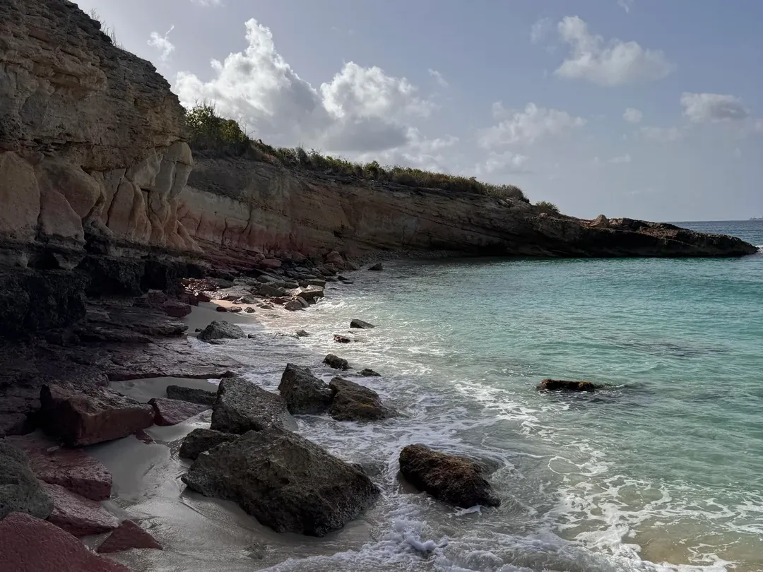 Rocky cove beneath layered sandstone cliffs at Cupecoy Beach, Sint Maarten